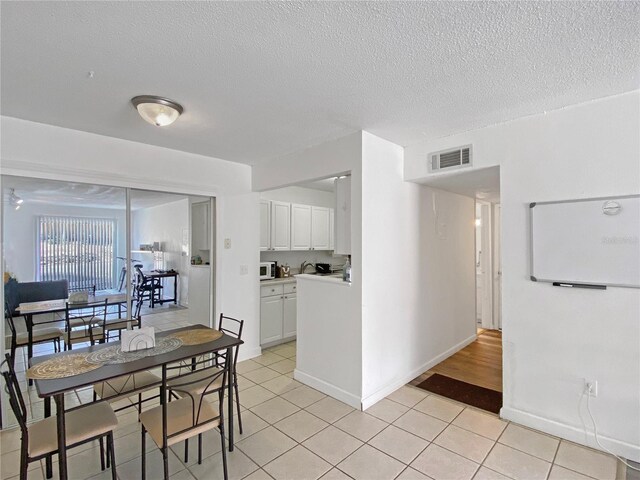 dining room featuring a textured ceiling, baseboards, light tile patterned flooring, and visible vents