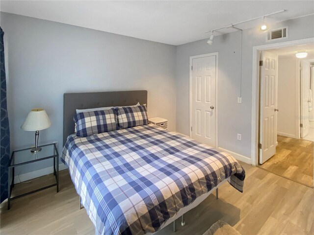 bedroom featuring baseboards, visible vents, track lighting, and light wood-style floors