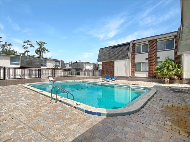 community pool with a patio and fence