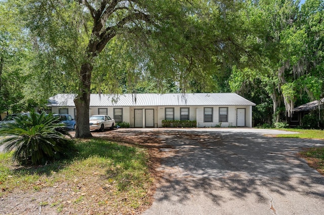 ranch-style home featuring metal roof and driveway