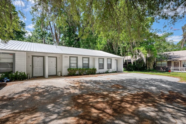 single story home with metal roof and driveway