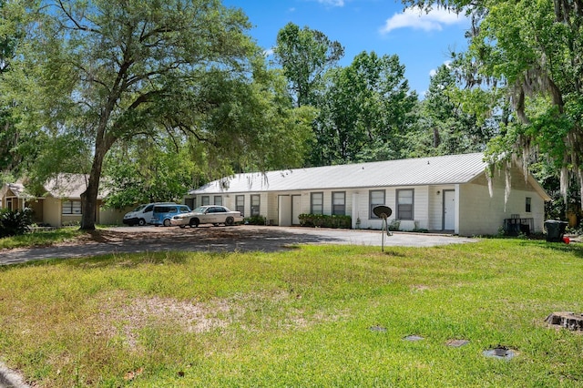 ranch-style home with metal roof and a front lawn
