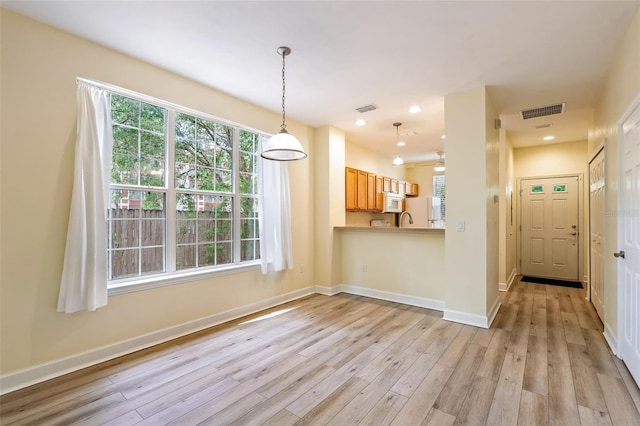 interior space with white appliances, visible vents, pendant lighting, and light wood finished floors