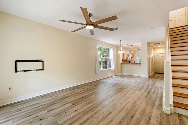 unfurnished living room featuring visible vents, stairs, baseboards, ceiling fan, and light wood finished floors