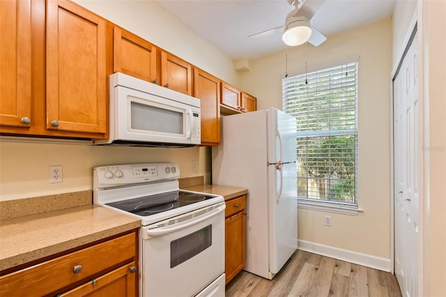 kitchen with brown cabinets, ceiling fan, light wood finished floors, and white appliances
