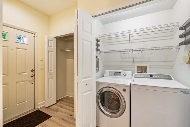 laundry area featuring washer and dryer, laundry area, baseboards, and light wood-style flooring