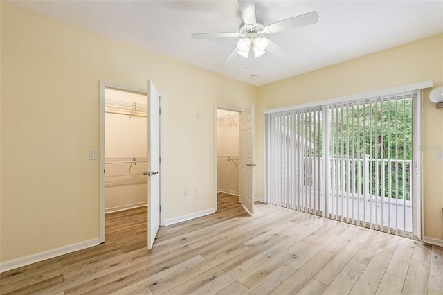 unfurnished bedroom with a closet, light wood-style floors, a spacious closet, and access to exterior