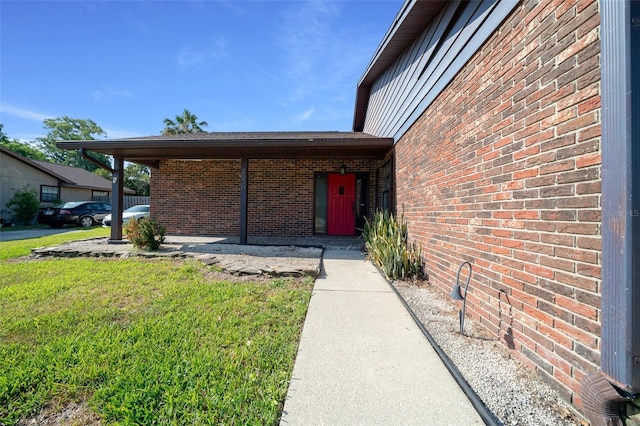 entrance to property with a lawn and brick siding