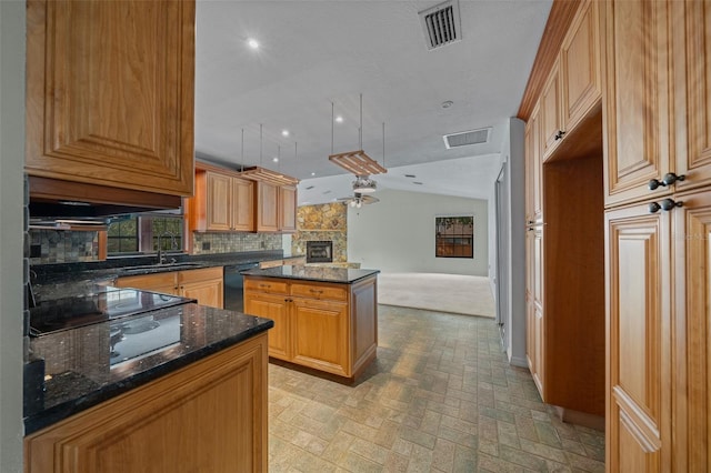 kitchen featuring visible vents, a center island, tasteful backsplash, black appliances, and dark stone countertops