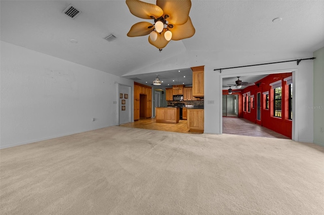 unfurnished living room featuring visible vents, ceiling fan, lofted ceiling, and light carpet