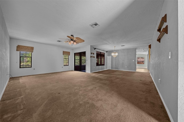 unfurnished living room featuring carpet flooring, a textured ceiling, a ceiling fan, baseboards, and visible vents