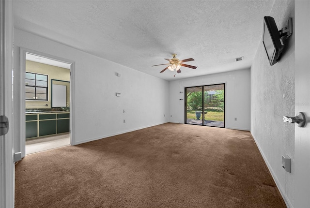 empty room featuring a textured ceiling, carpet, a ceiling fan, baseboards, and visible vents