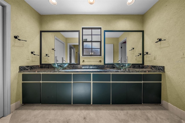 full bath with a sink, carpet floors, a textured wall, and double vanity