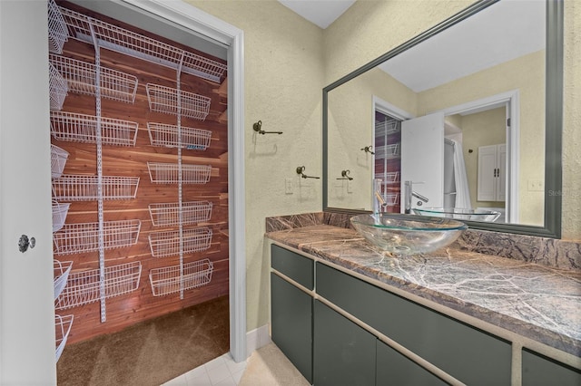 bathroom featuring vanity, a textured wall, and tile patterned floors