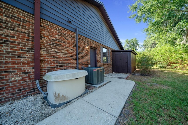 view of property exterior featuring brick siding, an outdoor structure, central air condition unit, and a shed