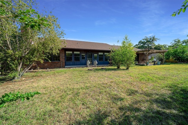 back of property with brick siding, a yard, and a pergola