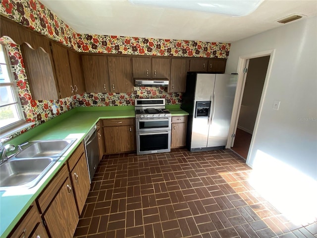 3900 NW 21st Ter, Gainesville, FL 32605 - kitchen featuring appliances with stainless steel finishes, light countertops, under cabinet range hood, a sink, and brick patterned floor