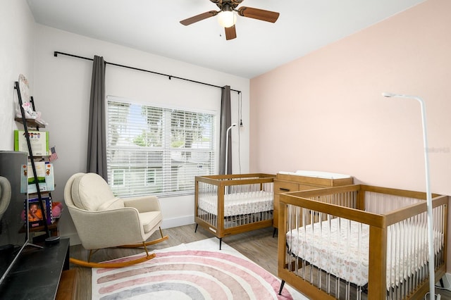 1488 NW 120th Way, Gainesville, FL 32606 - bedroom featuring a crib, ceiling fan, and wood finished floors
