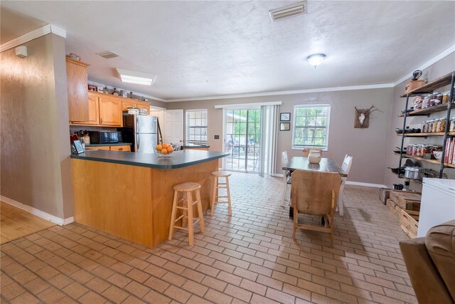 5876 SW 52nd Ter, Lake Butler, FL 32054 - kitchen featuring black microwave, freestanding refrigerator, a peninsula, visible vents, and ornamental molding