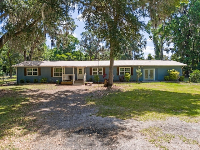single story home with a porch, driveway, french doors, metal roof, and a front lawn