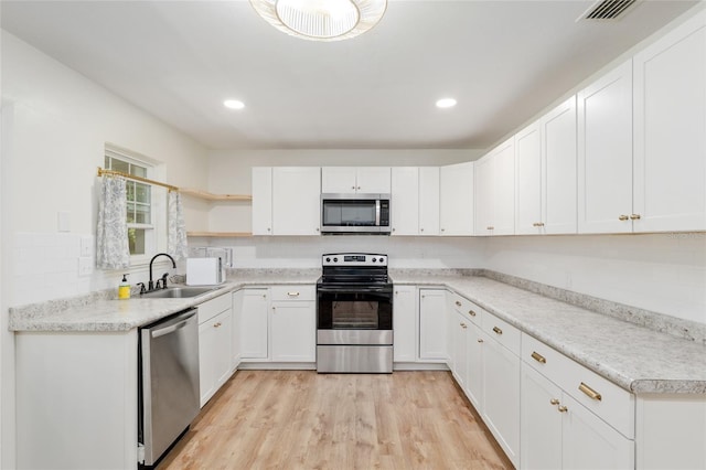 kitchen featuring a sink, open shelves, appliances with stainless steel finishes, and white cabinetry