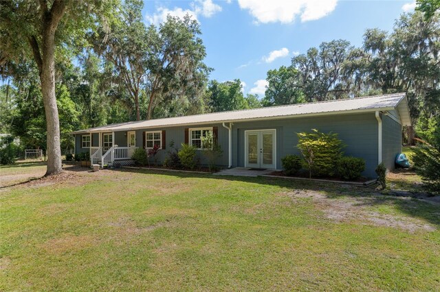 single story home featuring a front lawn, covered porch, french doors, and metal roof