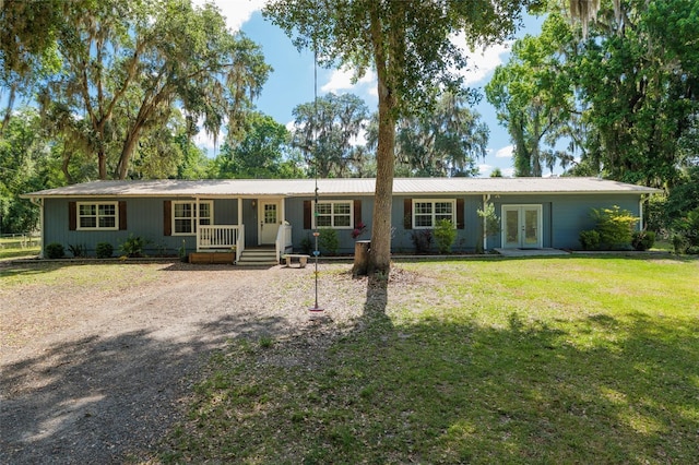 single story home featuring covered porch, a front yard, french doors, metal roof, and driveway