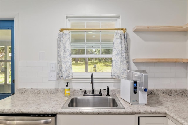 kitchen with stainless steel dishwasher, backsplash, open shelves, and a sink