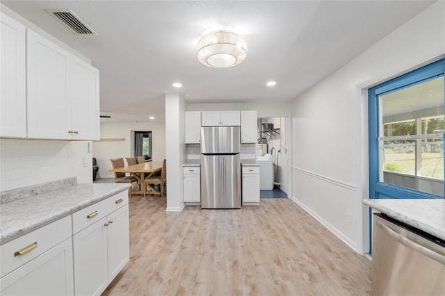 kitchen with visible vents, light wood-style floors, white cabinets, appliances with stainless steel finishes, and backsplash
