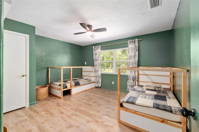 bedroom featuring visible vents, baseboards, ceiling fan, and wood finished floors