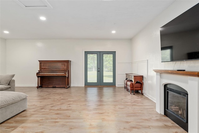 living area with recessed lighting, a glass covered fireplace, and light wood-style floors