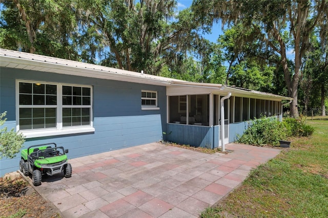 rear view of property featuring a sunroom, a patio area, and metal roof