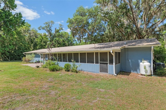rear view of property featuring metal roof, a sunroom, central air condition unit, a yard, and a patio