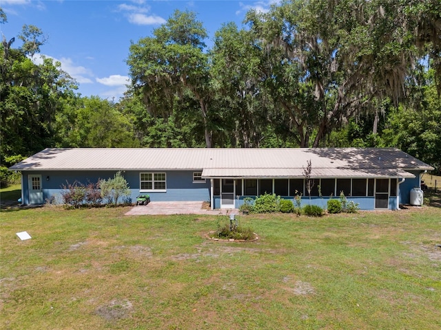 view of front of property featuring a sunroom, a front lawn, and metal roof