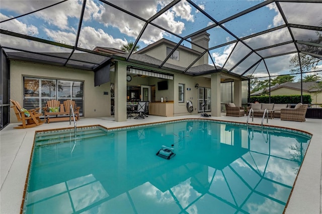 pool with an outdoor living space, glass enclosure, and a patio