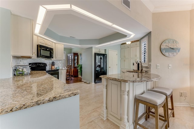 kitchen featuring visible vents, decorative backsplash, a peninsula, a sink, and black appliances