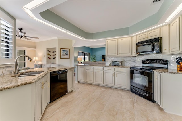 kitchen with light stone countertops, a sink, a peninsula, decorative backsplash, and black appliances
