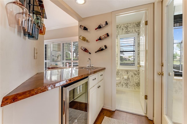 bar featuring a sink, beverage cooler, light wood-style flooring, indoor wet bar, and a wealth of natural light