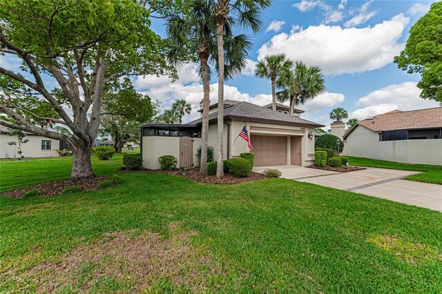 mid-century home featuring an attached garage, stucco siding, concrete driveway, and a front lawn