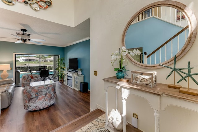 interior space with a ceiling fan, wood finished floors, stairway, baseboards, and ornamental molding