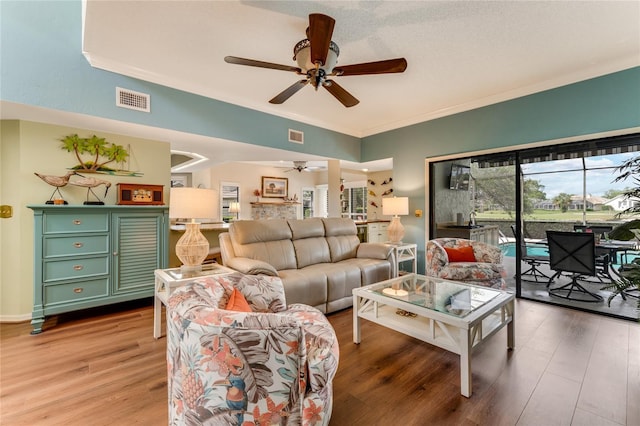 living room with visible vents, ornamental molding, light wood finished floors, and ceiling fan