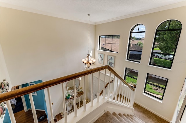 staircase featuring an inviting chandelier, baseboards, and crown molding