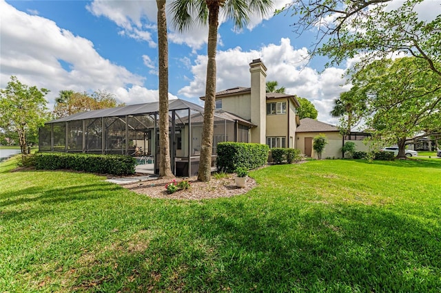 rear view of house featuring a lawn, glass enclosure, and stucco siding