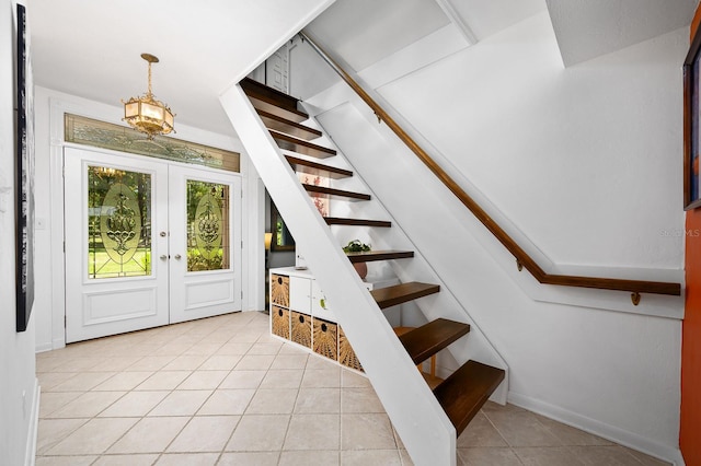 foyer entrance featuring french doors, baseboards, stairs, and light tile patterned floors
