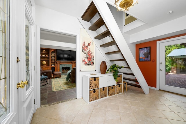 foyer featuring a premium fireplace, light tile patterned floors, and stairway
