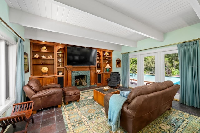 living room with stone tile flooring, beam ceiling, and a fireplace