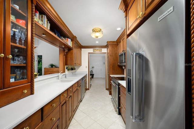 kitchen featuring glass insert cabinets, light countertops, a sink, light tile patterned floors, and stainless steel appliances