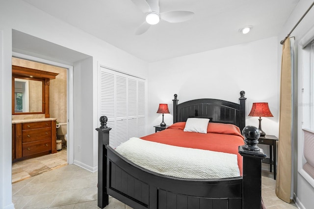 bedroom featuring ceiling fan, light tile patterned floors, baseboards, a closet, and ensuite bath
