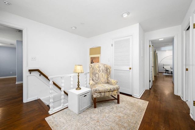 sitting room featuring baseboards, visible vents, wood finished floors, and an upstairs landing