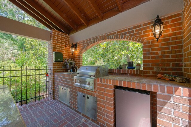 view of patio featuring an outdoor kitchen, fence, a sink, and a grill